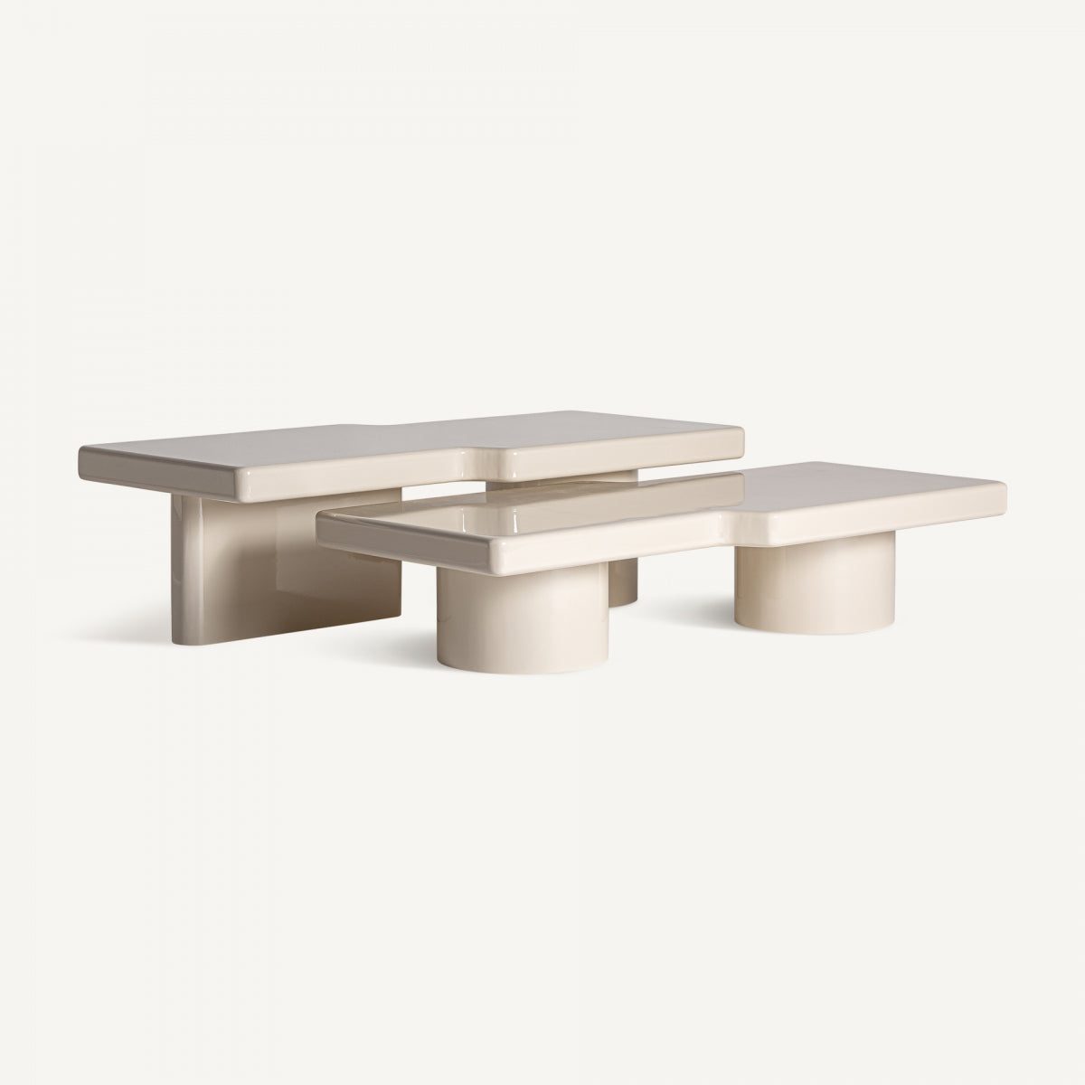 Mesa baja en beige con formas curvas y bases cilíndricas en disposición asimétrica