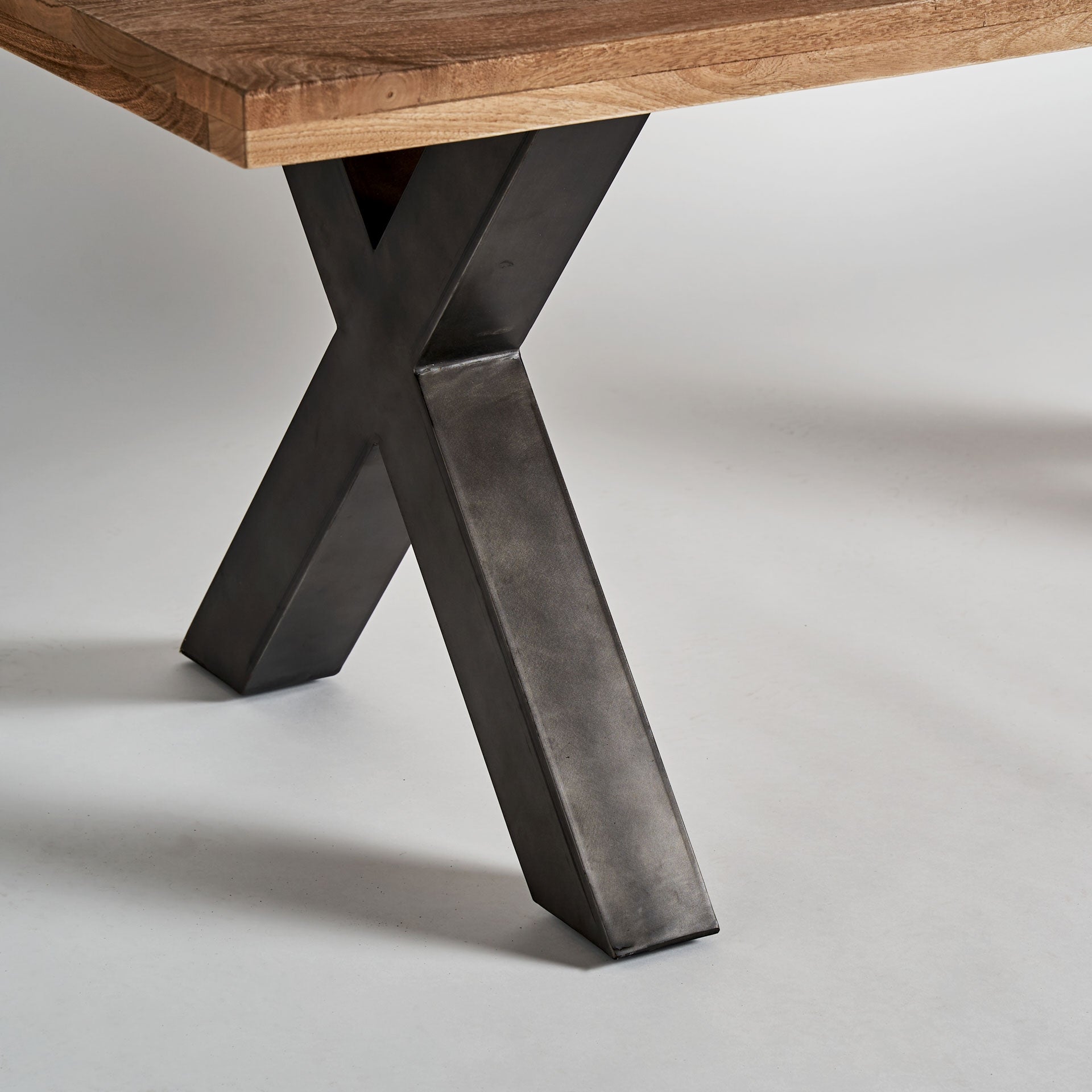 Detalle de la pata metálica en cruz de la mesa Gard, estructura de hierro negro estilo industrial, VICAL boutique interiorismo