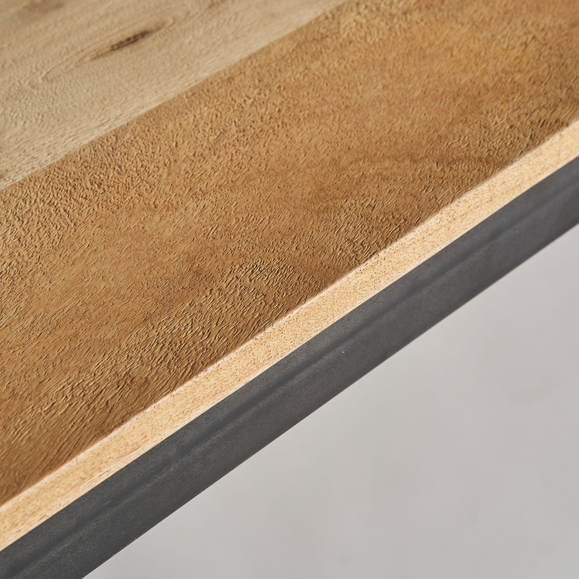 Primer plano del canto del tablero en madera de mango natural de la mesa comedor Courry.