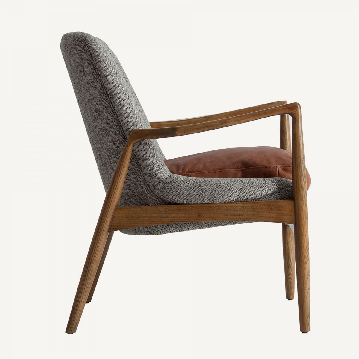 Butaca ELATI en vista lateral izquierda, brazos curvos de madera y perfil ergonómico, diseño nórdico con cojín de cuero.