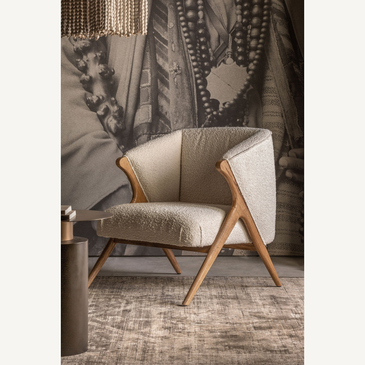 Sillón de madera y bouclé frente a mural artístico, ambiente cálido y elegante, boutique interiorismo Vical