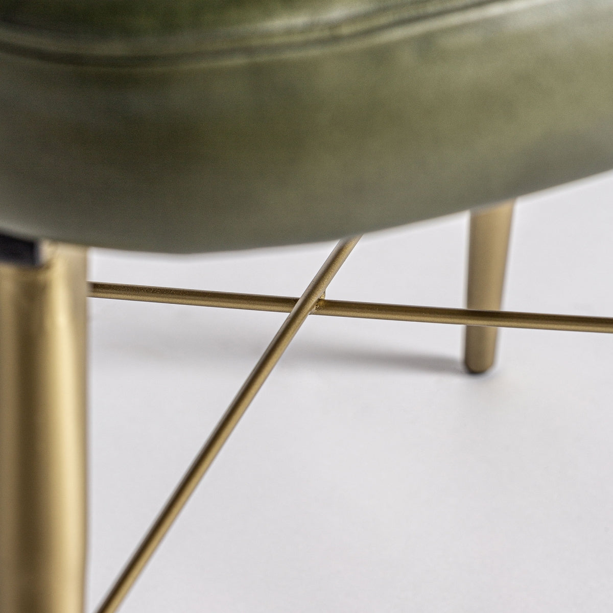 Detalle de la estructura metálica dorada en forma cruzada bajo el asiento
