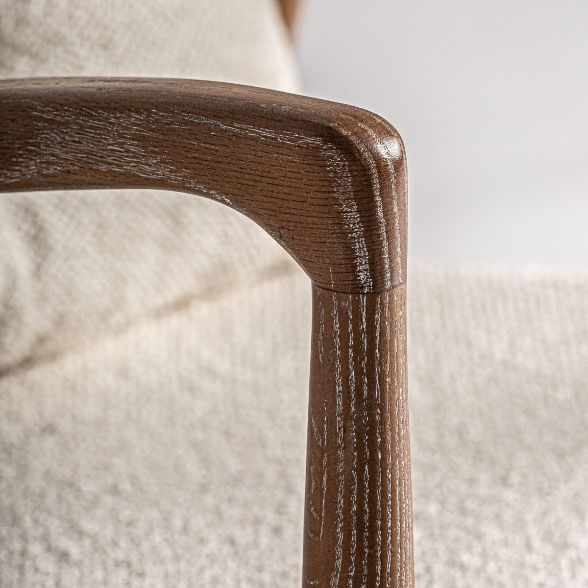 Detalle del apoyabrazos curvado en madera natural con veta visible, diseño refinado