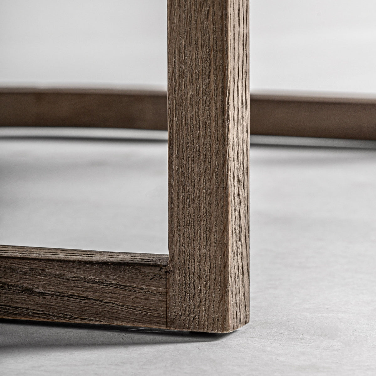 Zoom sobre la base curva en madera natural del sillón LEIWEN, diseño robusto y elegante