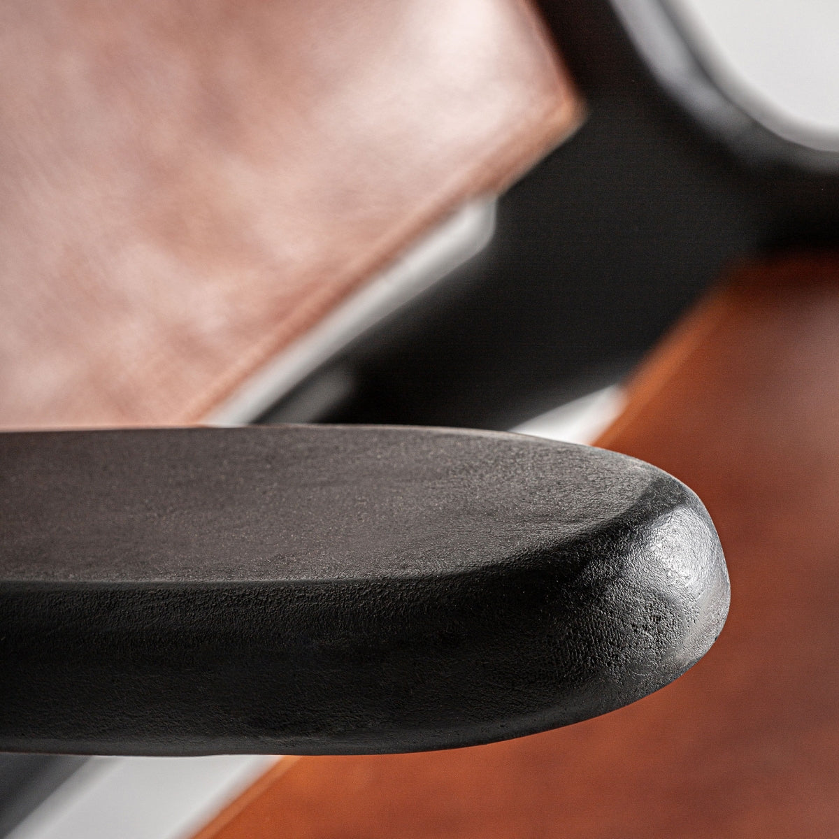 Detalle del apoyabrazos en madera negra del sillón con acabado mate.