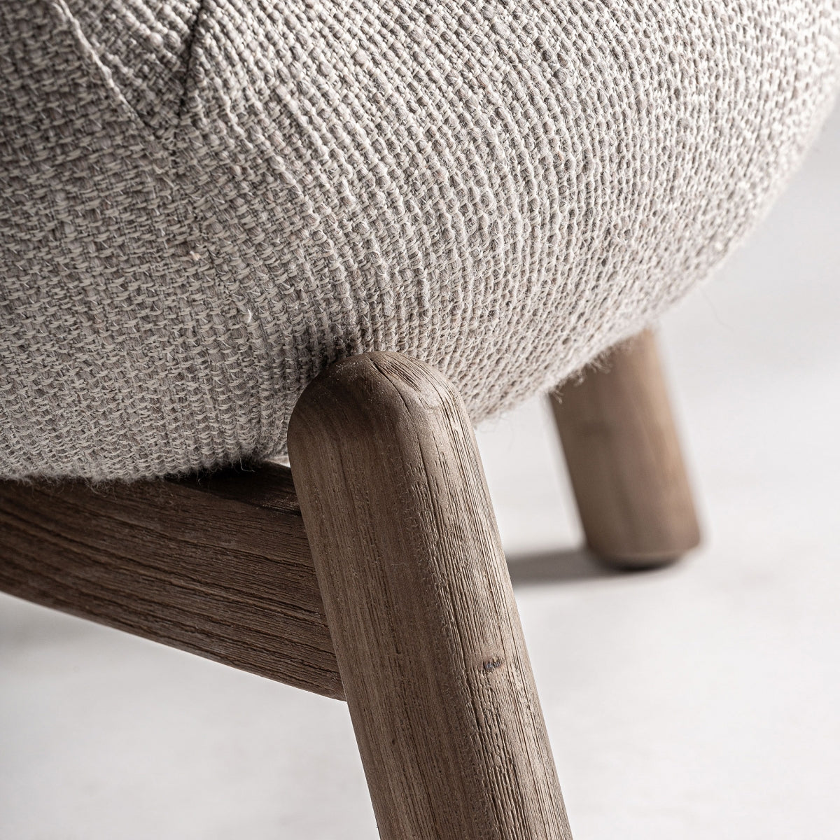 Detalle de la pata de madera vista con veta natural y unión del tapizado, estilo orgánico rústico