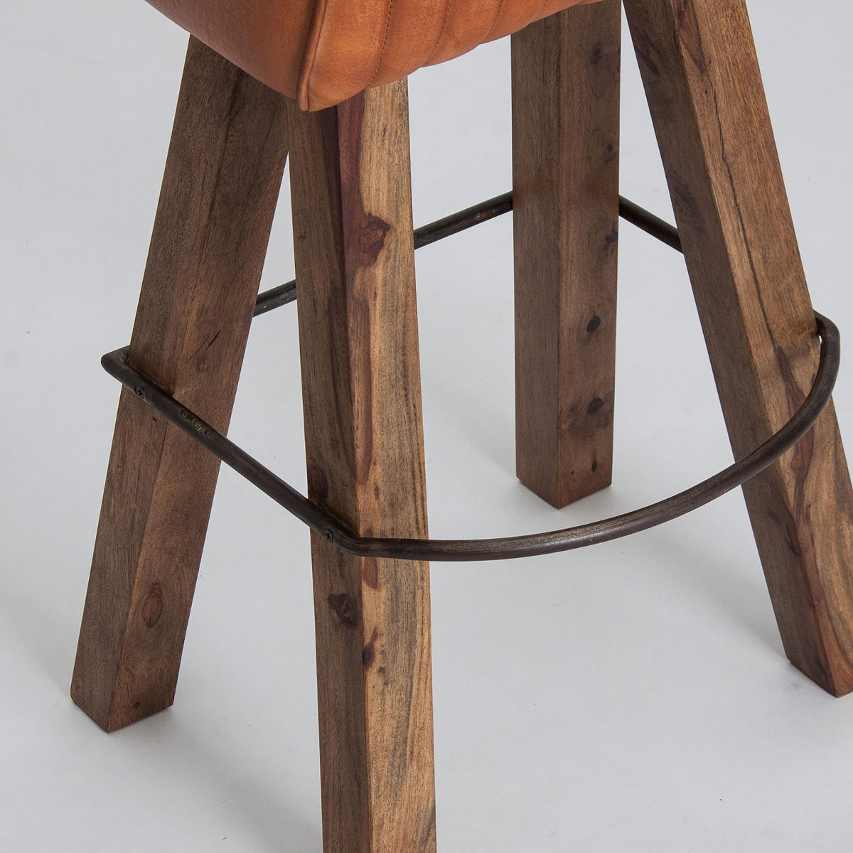 Detalle de la estructura del taburete con patas de madera natural y aro metálico oscuro.