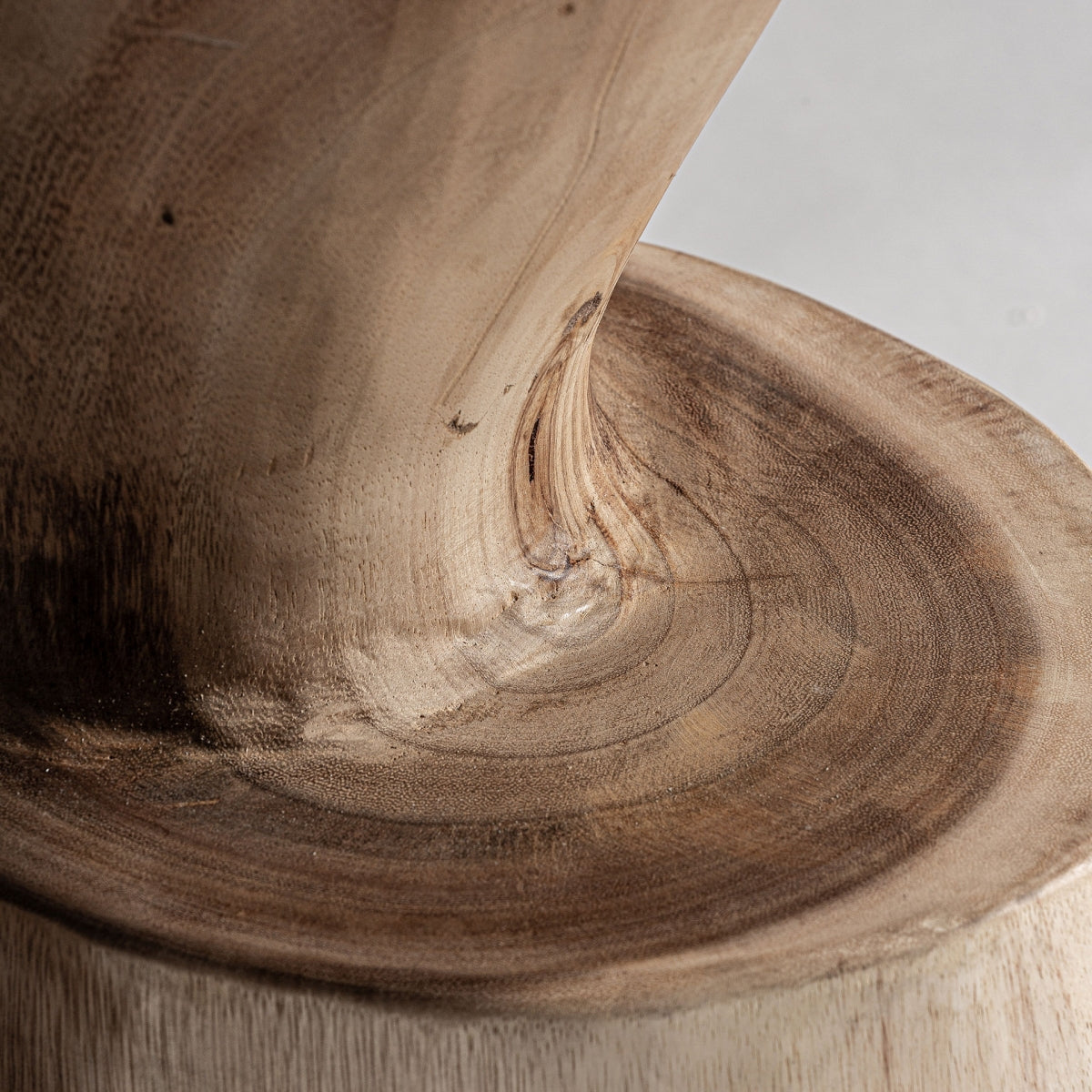 Detalle del asiento curvo tallado en madera, con vetas visibles y acabado natural.