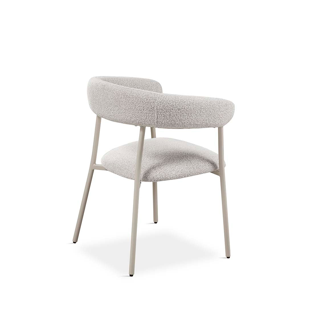 Silla tapizada en bouclé claro vista trasera, con respaldo ergonómico curvo y patas metálicas. Ideal para salones de estilo nórdico. Boutique Interiorismo.