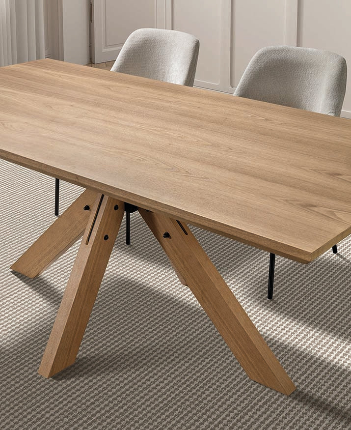 Mesa rectangular en madera natural con base geométrica triangular central — diseño moderno con fuerza escultórica de Boutique Interiorismo.

