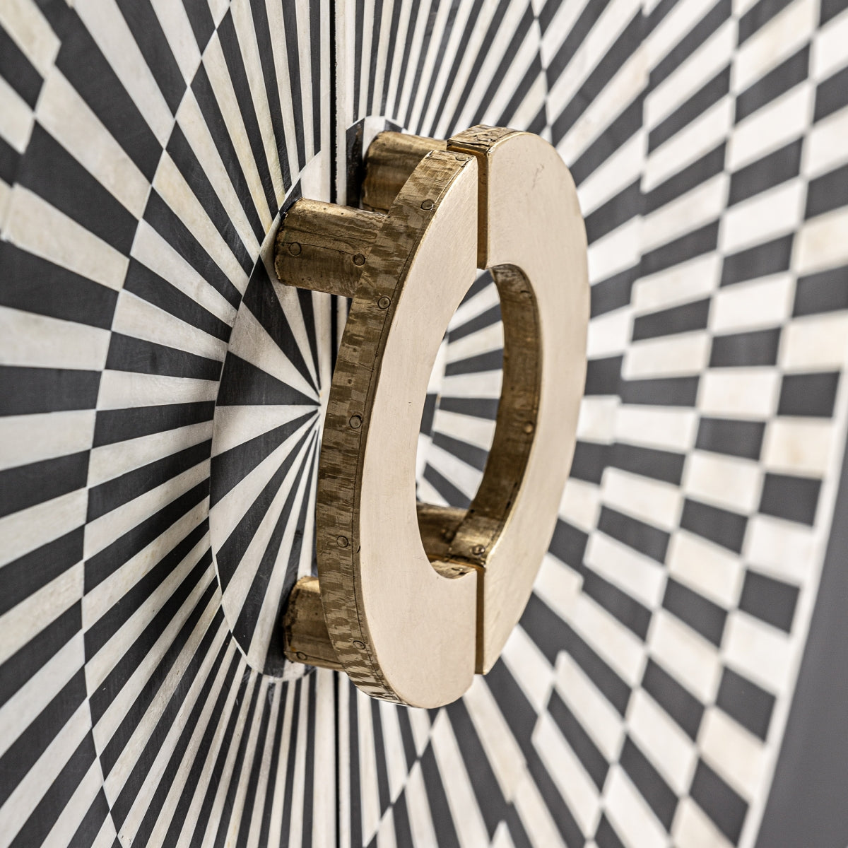Tirador circular dorado sobre diseño óptico, inspiración art déco.
