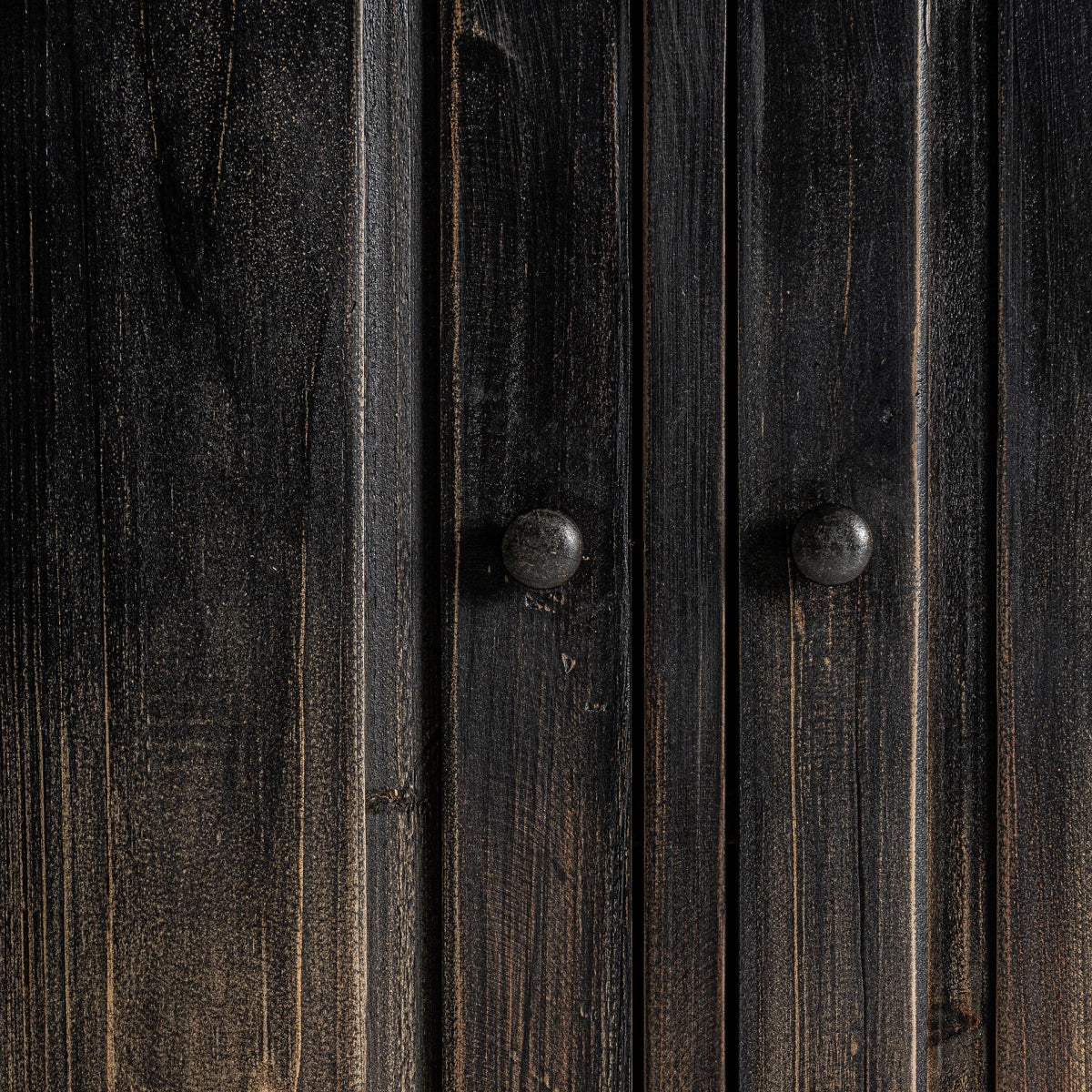 pomos metálicos rústicos en negro sobre puertas de madera patinada.