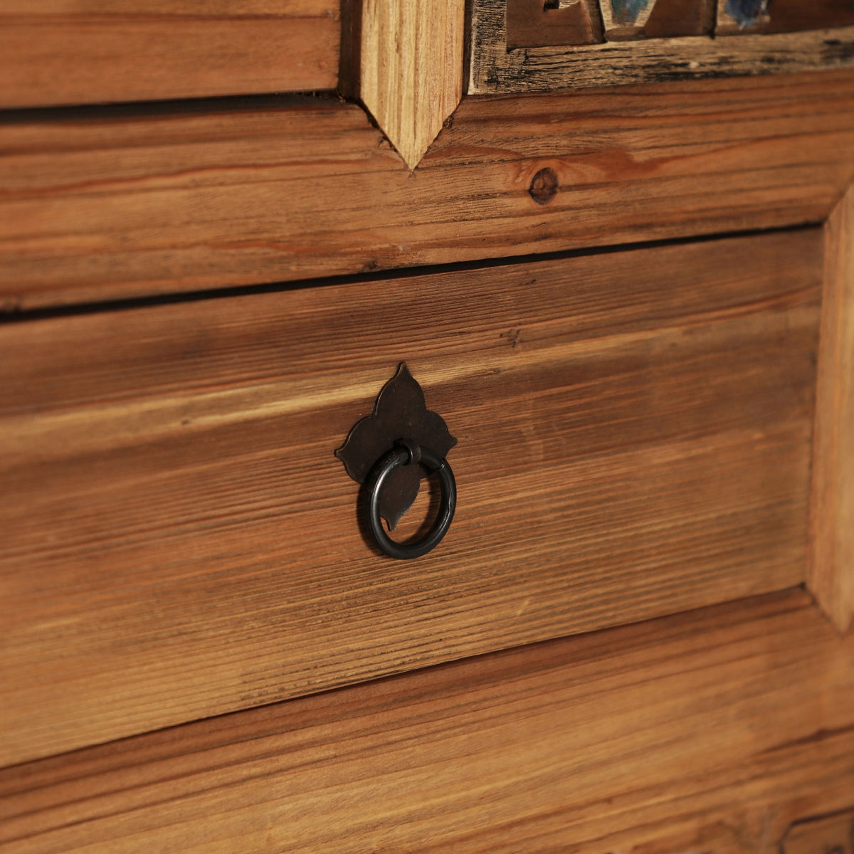 tirador de anilla en hierro forjado sobre cajón en madera natural.