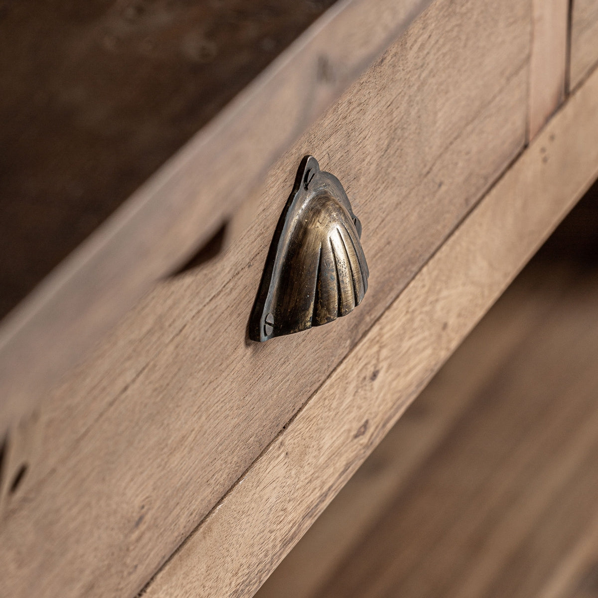 Tirador de latón envejecido con forma de concha en cajón de madera.
