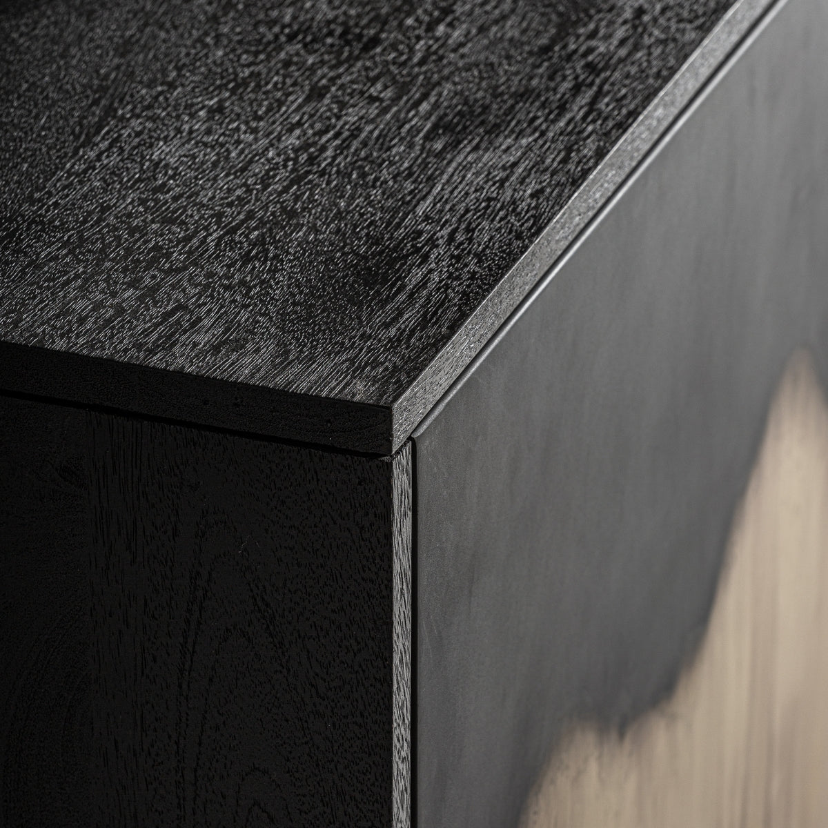 Detalle del sobre del aparador en madera negra texturizada. Acabado superior elegante y moderno.