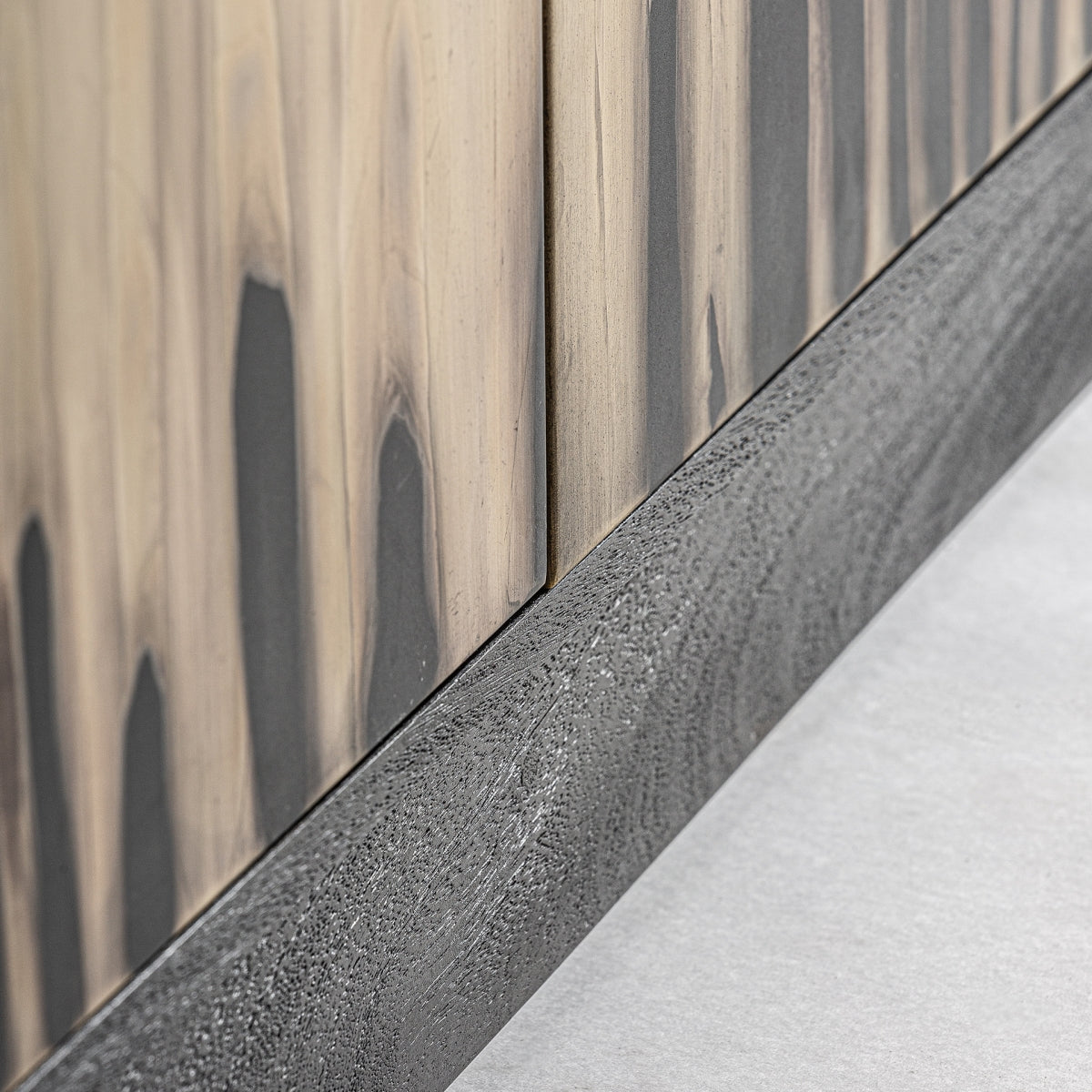 Vista de detalle de la base del aparador en madera oscura con textura y acabado natural.