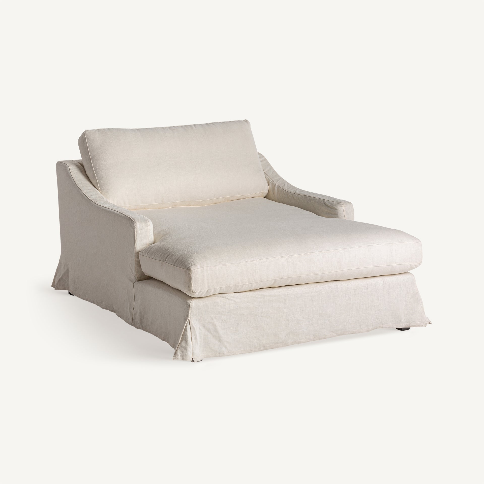 Chaise longue blanca vista 3/4 con faldón, cojines mullidos y diseño relajado.