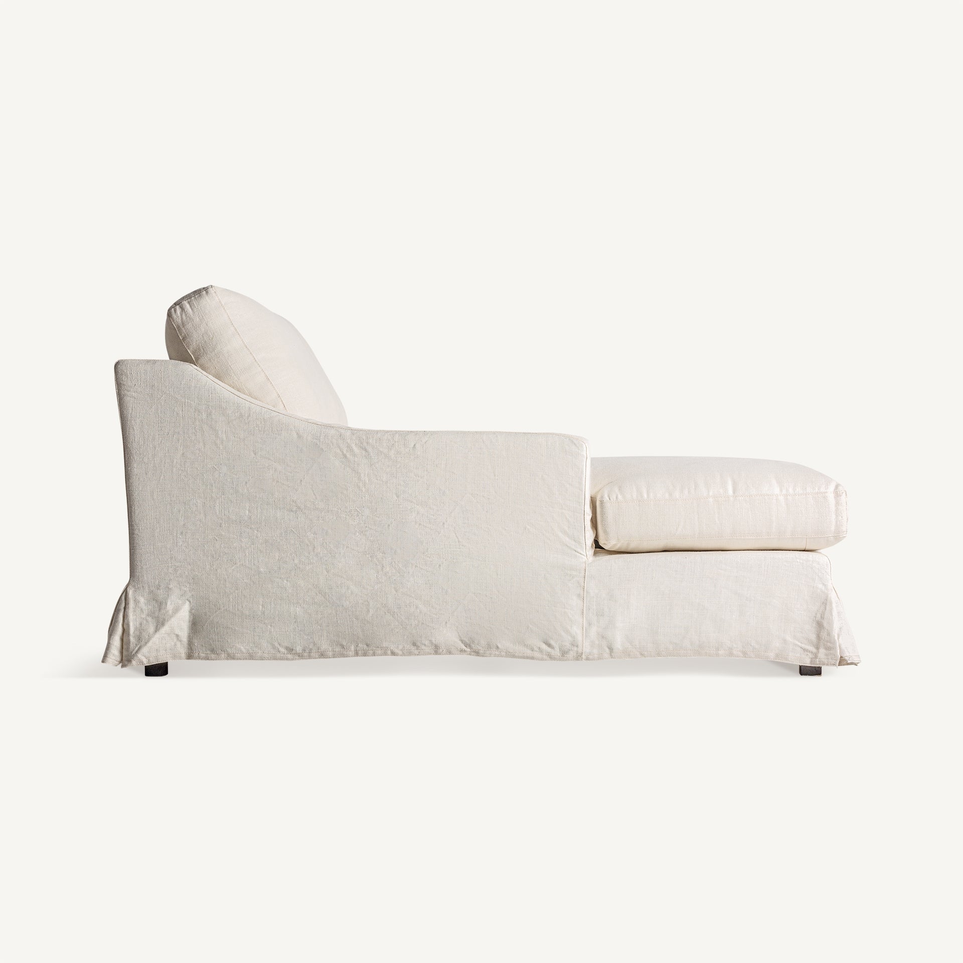 Perfil lateral de chaise longue con brazos curvos tapizados en lino natural.