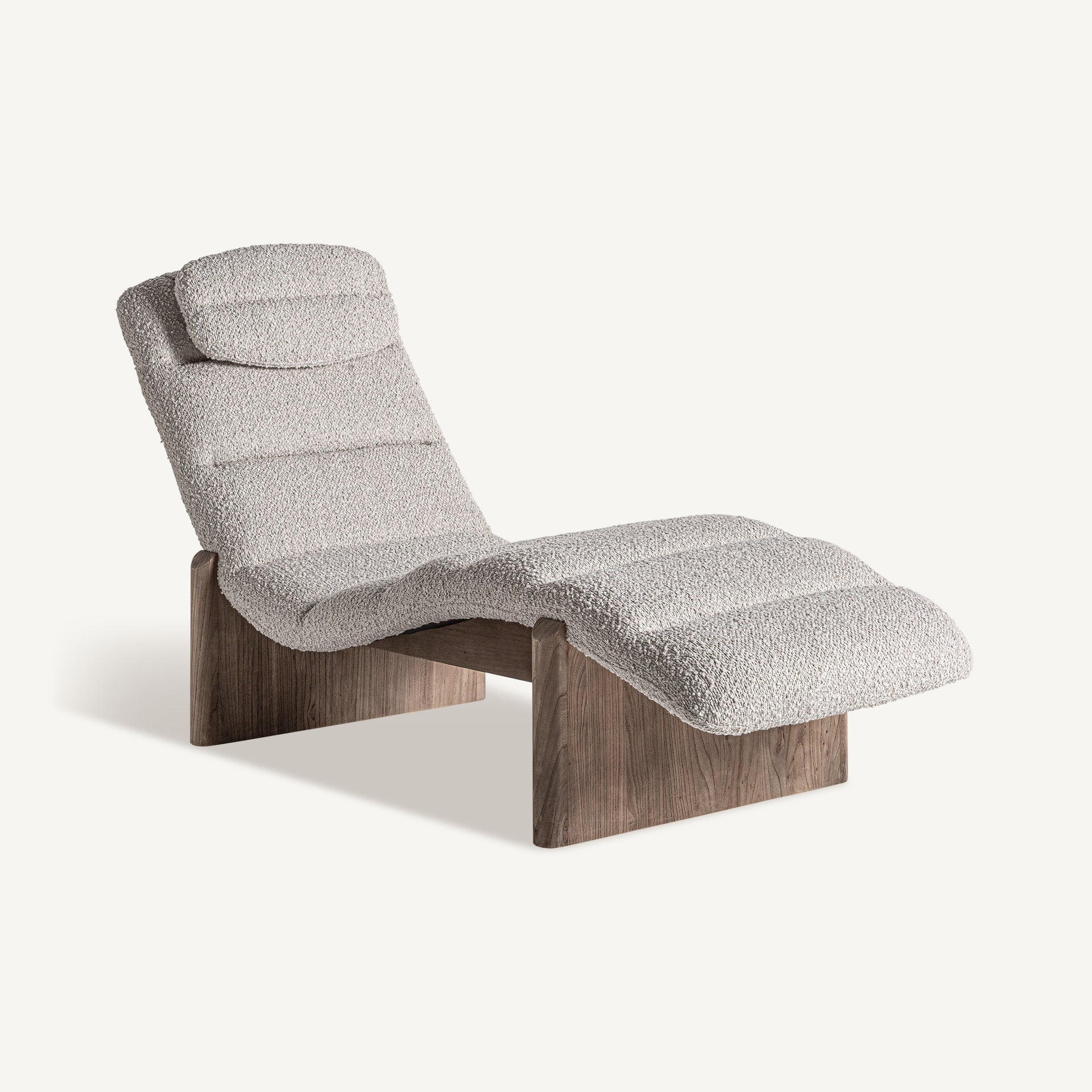 Chaise longue vista 3/4 con tapizado bouclé beige y base de madera de roble. Diseño ergonómico moderno.
