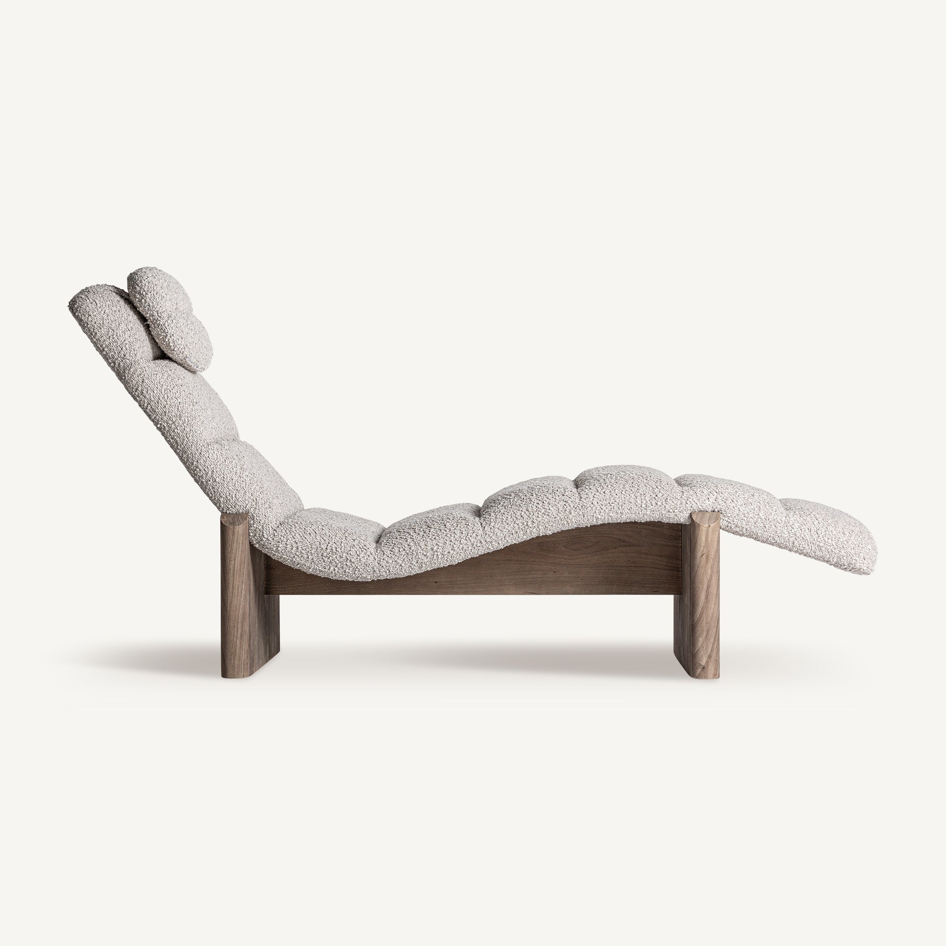Vista lateral de chaise longue con curvatura ergonómica y patas de madera de roble natural.