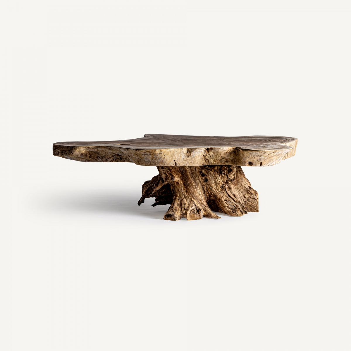 Mesa de centro con base de tronco natural y tapa de madera maciza orgánica, de gran fuerza escultórica.