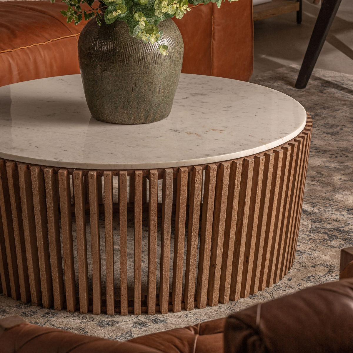 Mesa de centro redonda en ambiente de salón, con estructura de madera y tablero de mármol blanco