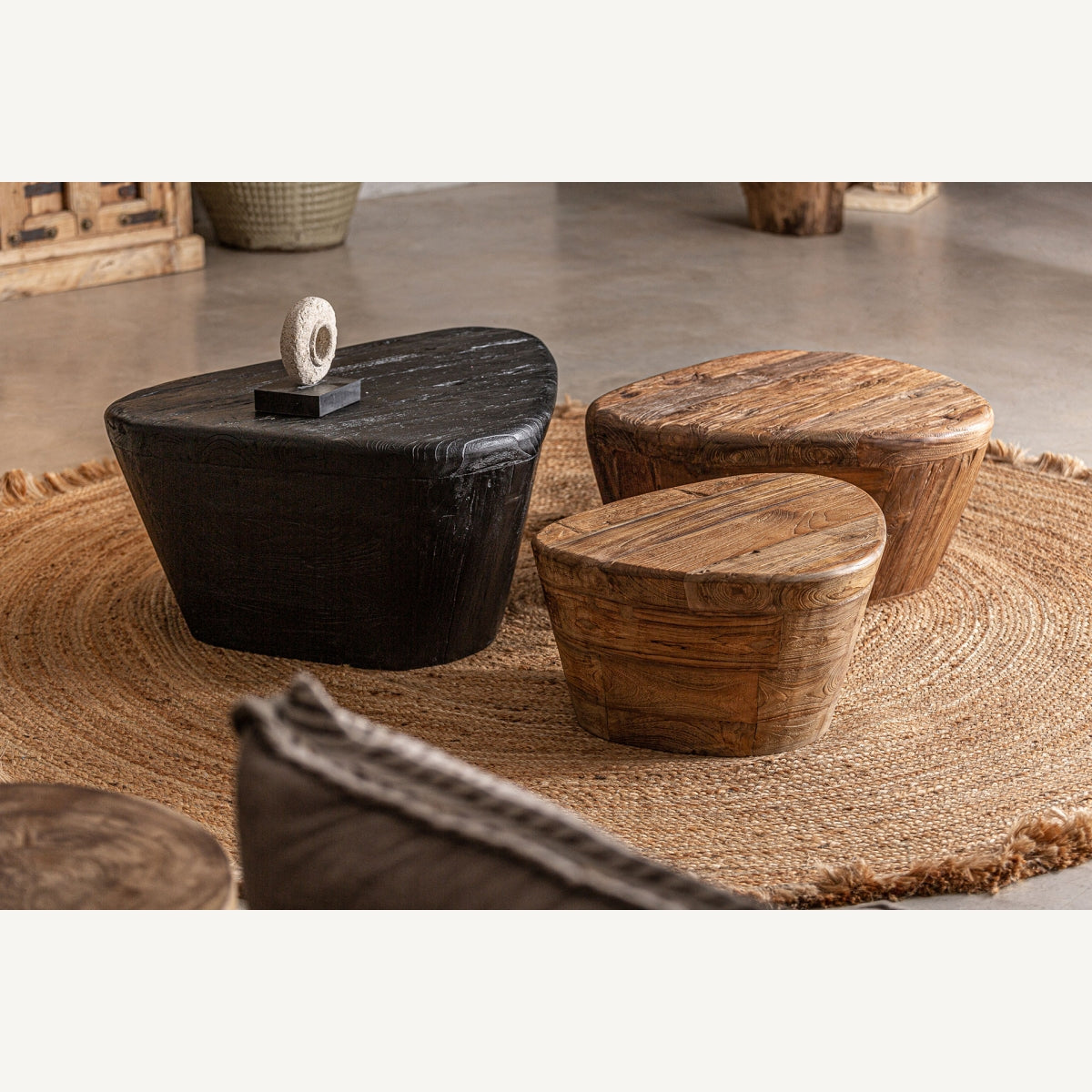 Ambiente bohemio con mesas de centro de formas orgánicas en madera natural y negra. Decoración con carácter.