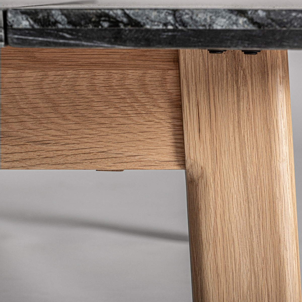 Detalle de la estructura inferior en madera clara bajo el sobre de piedra negra, diseño Nara