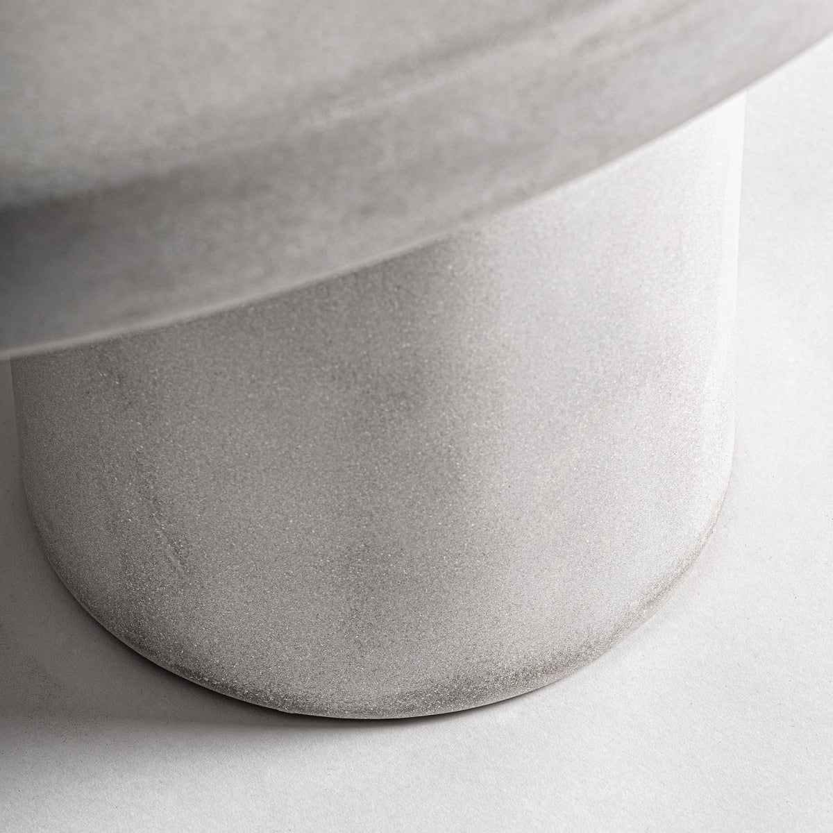 Detalle de la base cilíndrica texturizada en hormigón blanco de la mesa CLES3, estilo escultórico moderno