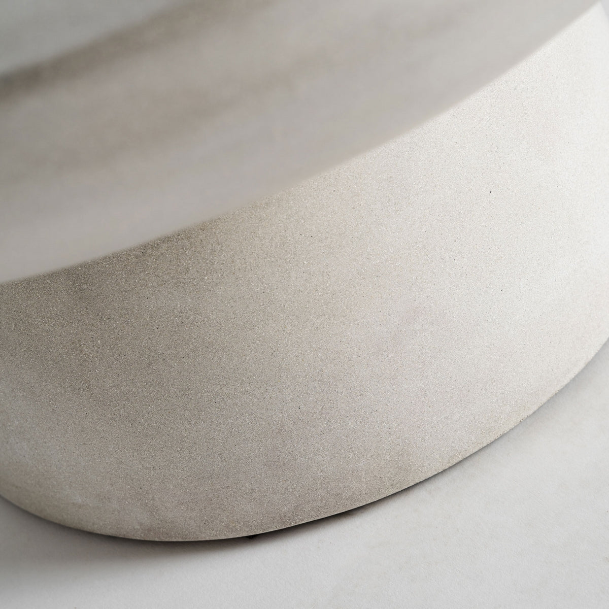 Primer plano de la base redondeada de la mesa CLESB, diseño contemporáneo con inspiración escultórica