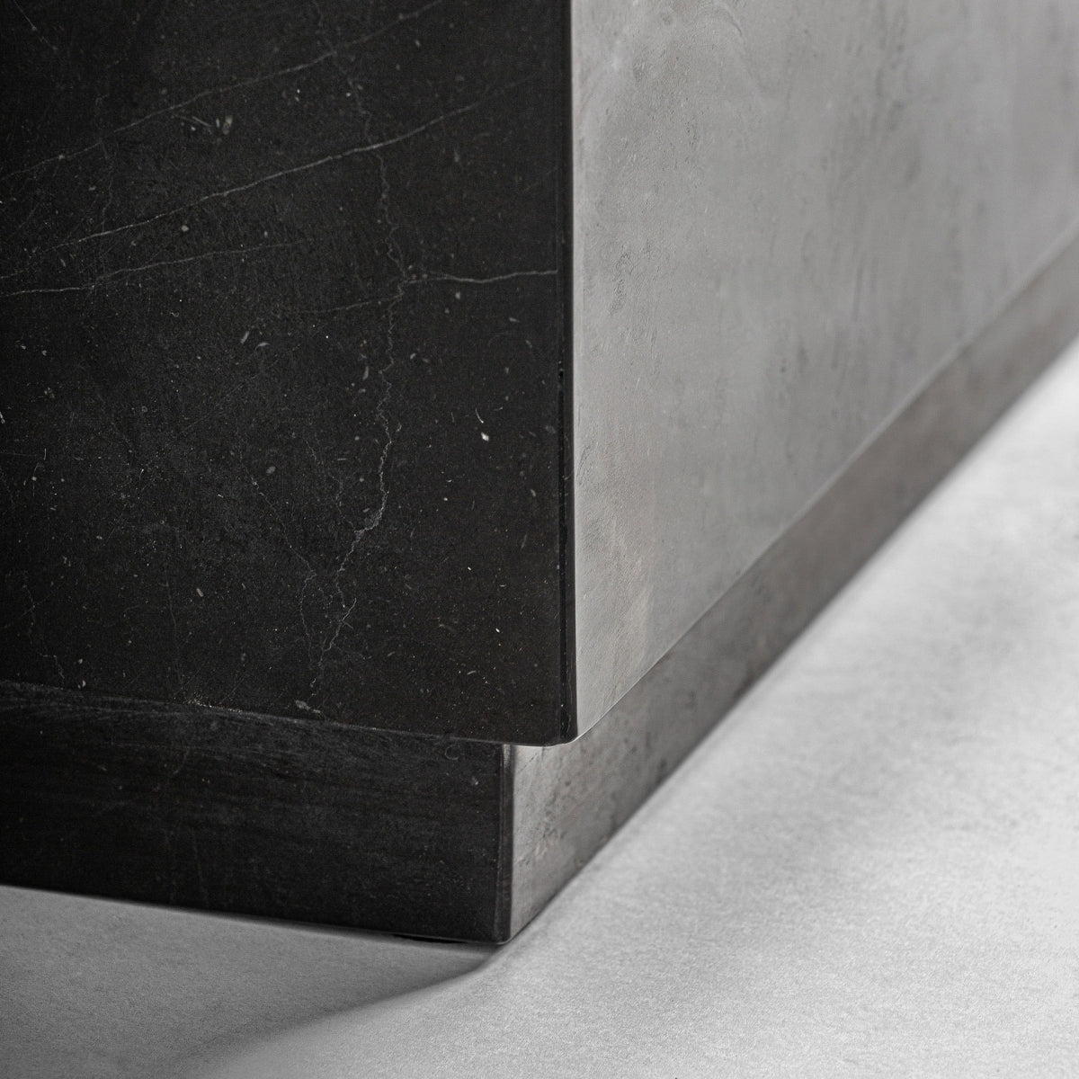 Detalle de la base de la mesa de mármol negro con juego de sombras y volumen sólido, diseño escultórico, boutique interiorismo VICAL