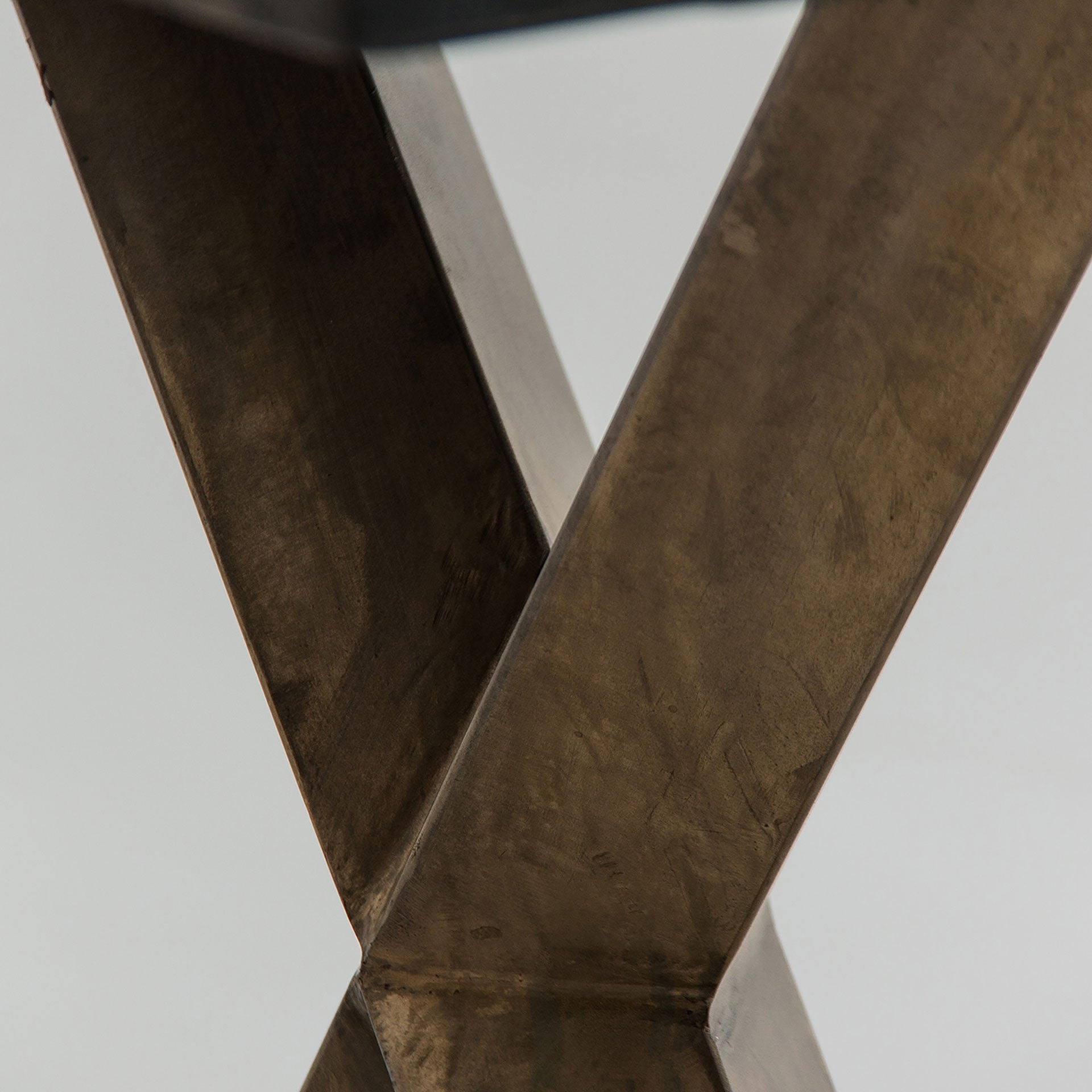 Detalle de las patas metálicas doradas en forma de X, estructura firme y sofisticada