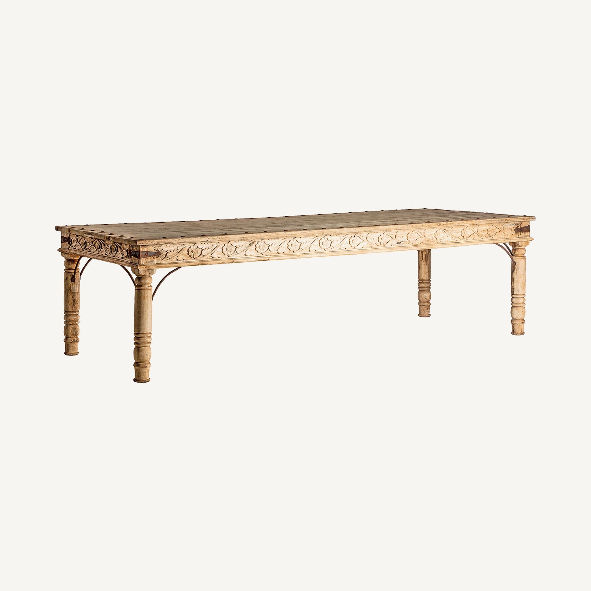 Vista en ángulo de mesa rectangular de madera con talla floral decorativa, ideal para comedores cálidos.