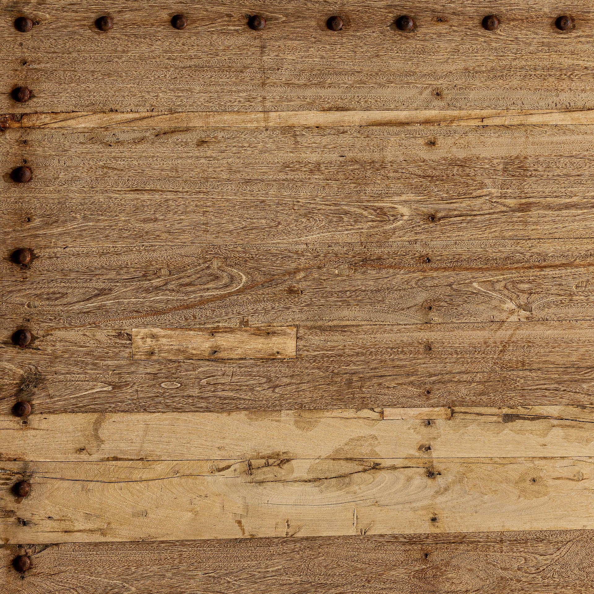 Plano del tablero con vetas naturales de madera y remaches industriales decorativos.