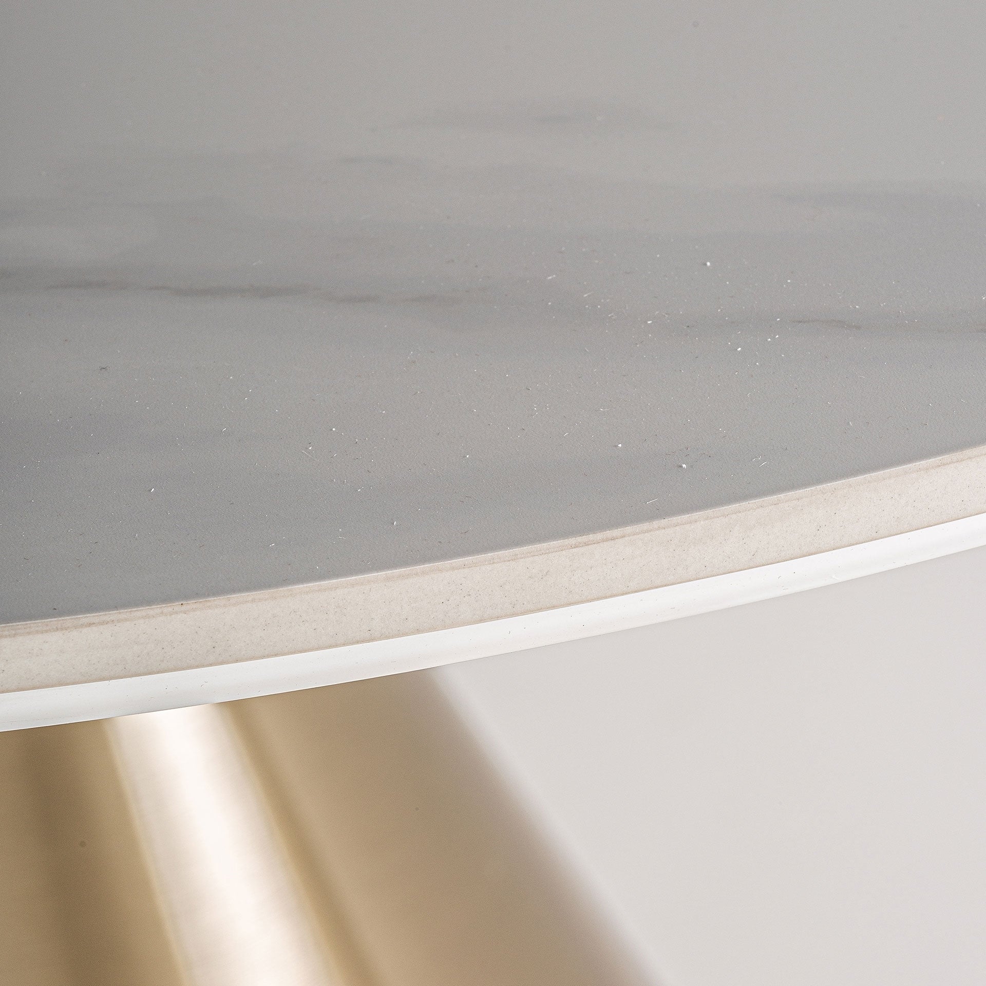 Detalle del canto y textura del porcelánico blanco en mesa redonda, estilo sofisticado y limpio