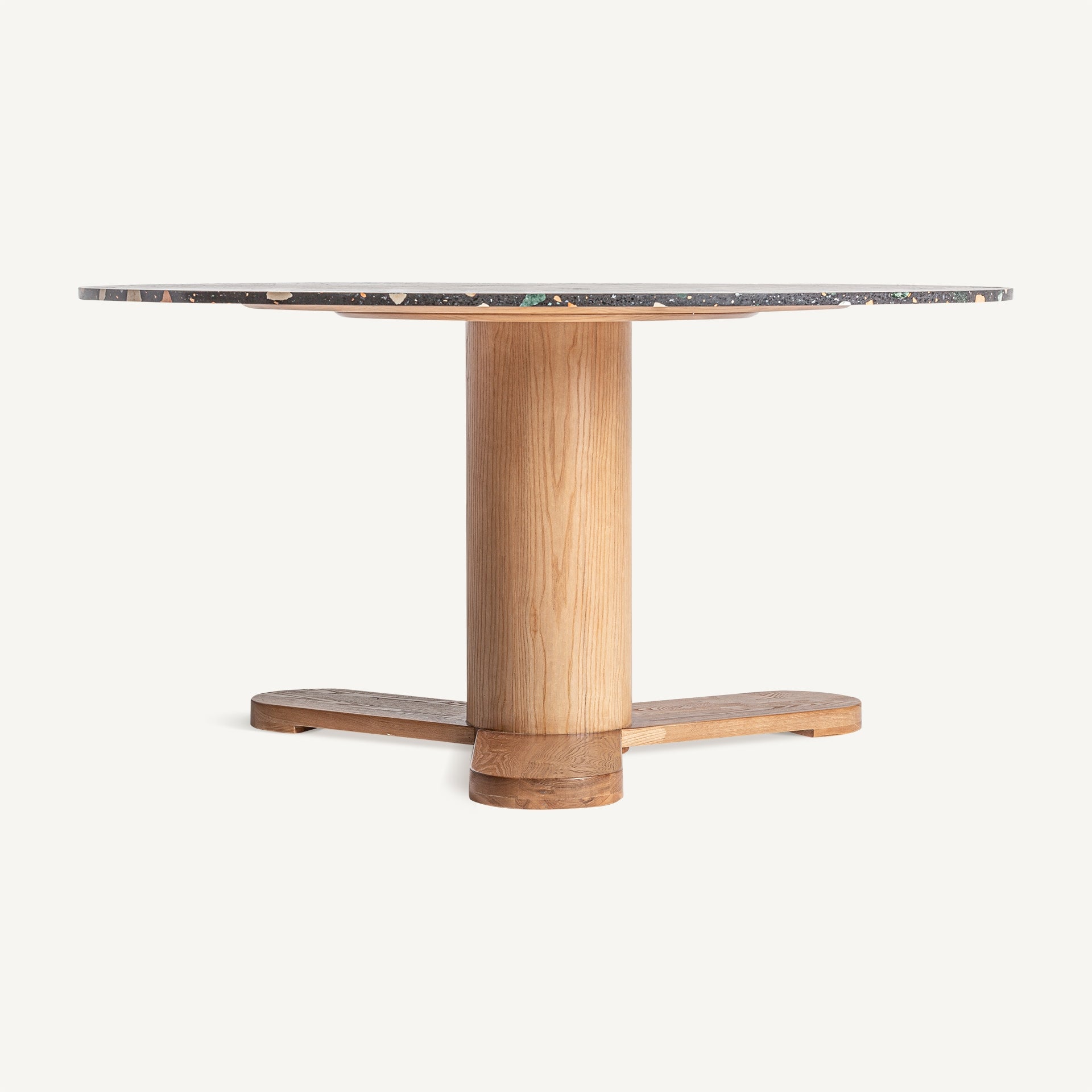 Mesa comedor redonda con sobre de terrazo negro multicolor y base central de madera natural – vista frontal