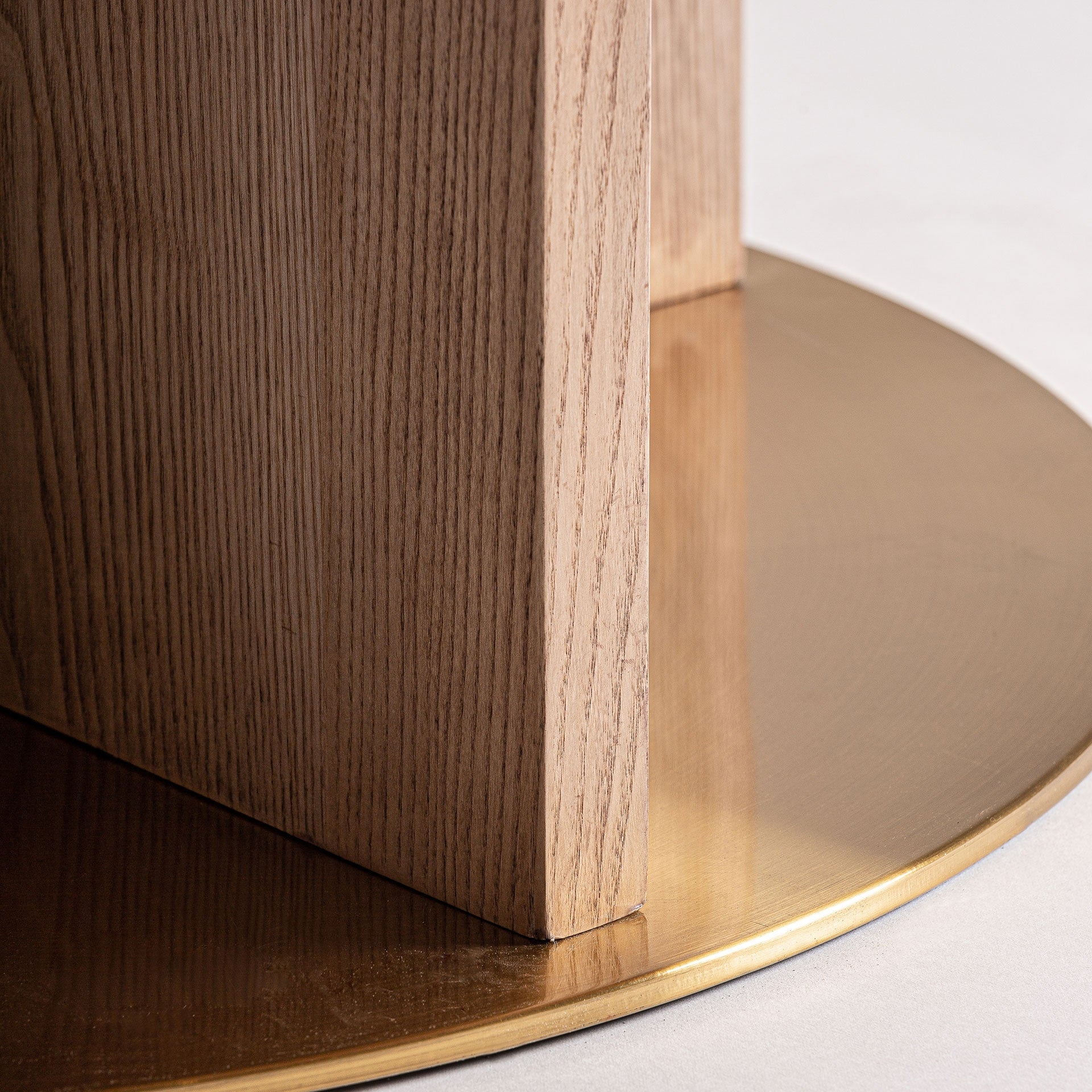 Detalle de la base circular de acero dorado que realza el diseño sofisticado y geométrico de la mesa comedor Alferce.