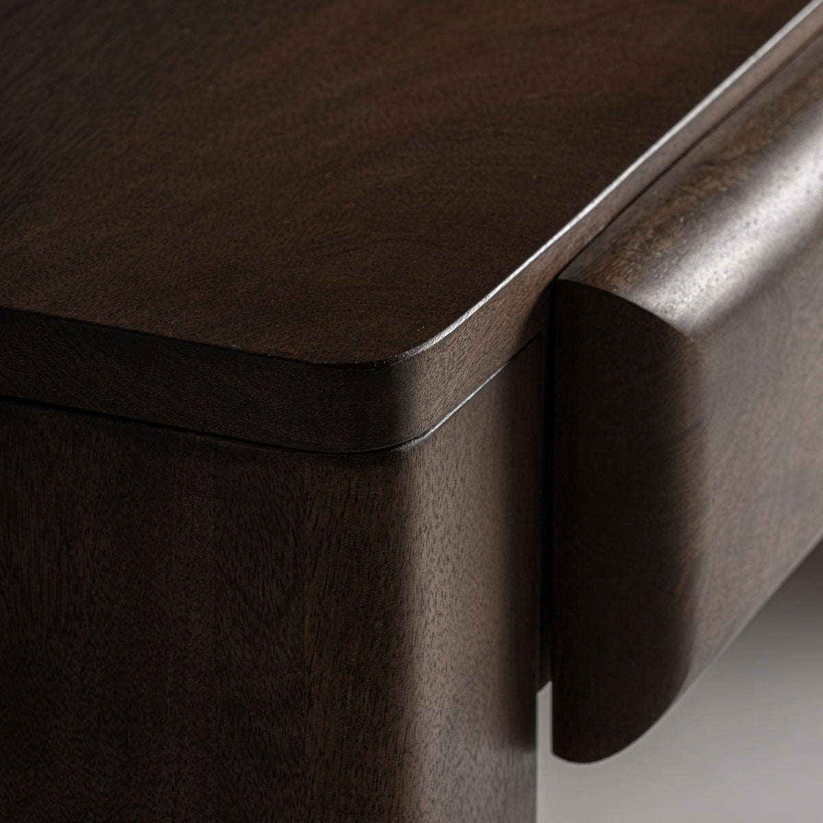 Detalle curvo de la esquina del escritorio art déco en madera natural de mango, líneas redondeadas y limpias