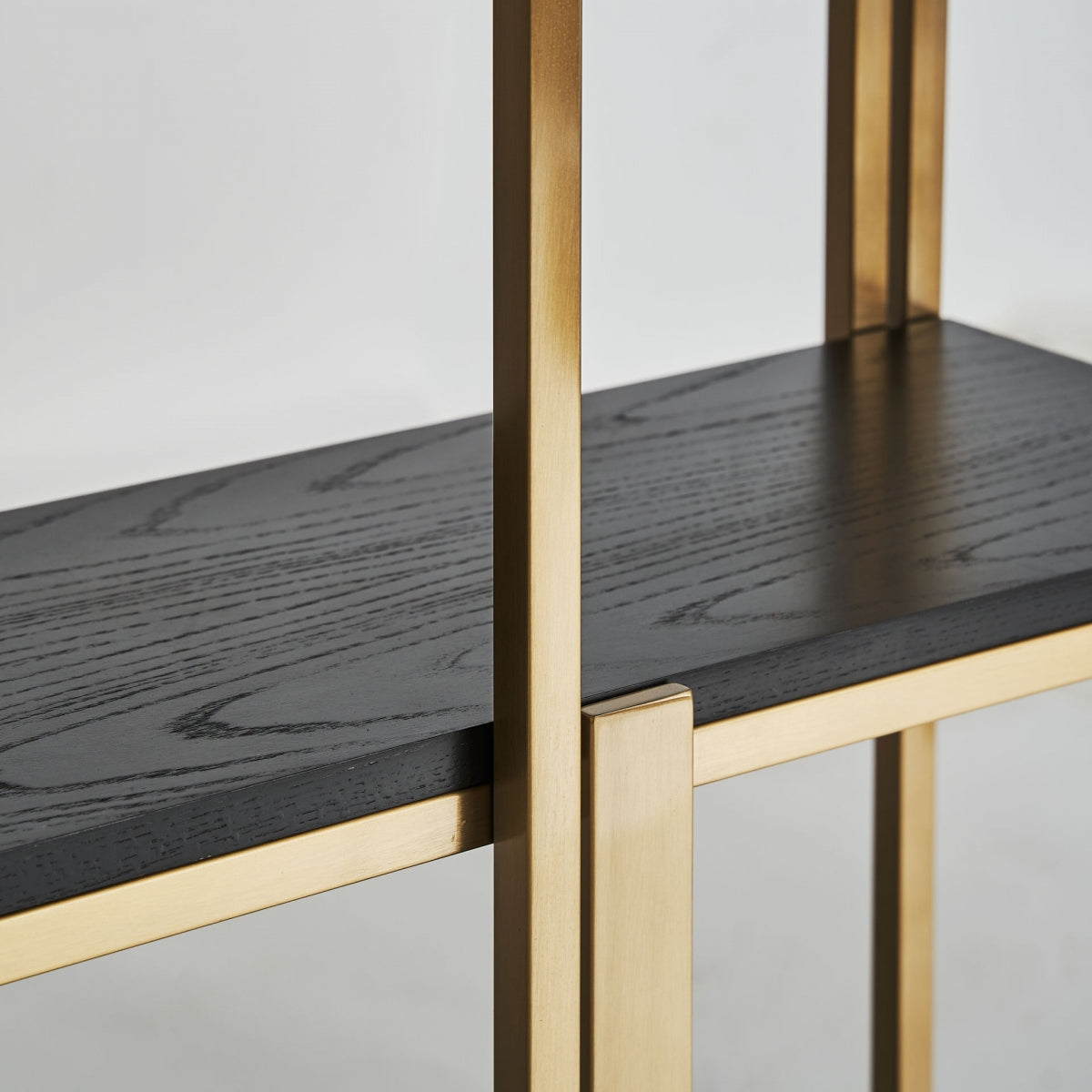 Detalle de la balda en madera negra con vetas visibles y estructura metálica dorada