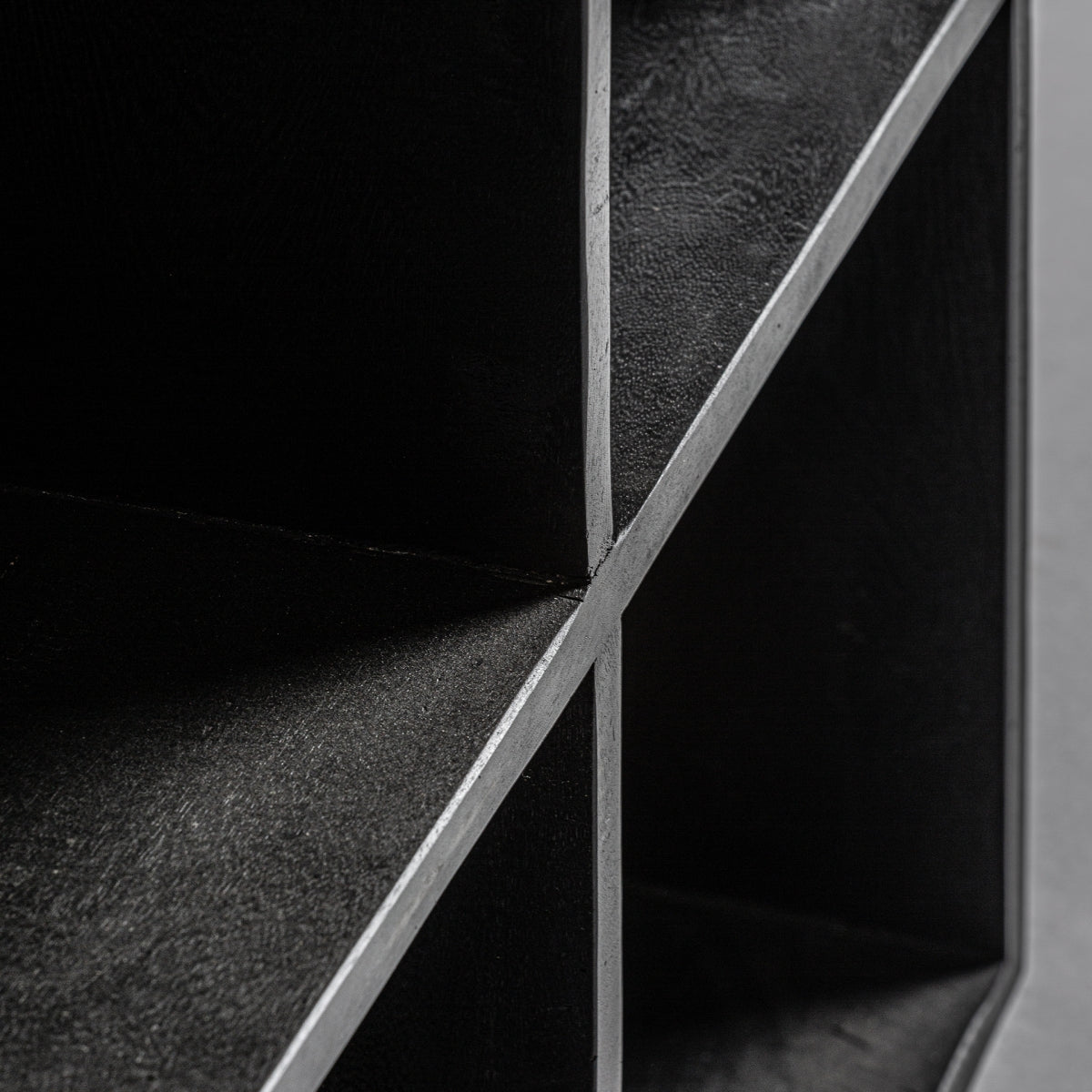 Detalle de cruce entre compartimentos de estantería Bayereut en madera de mango negra, textura artesanal, Vical boutique