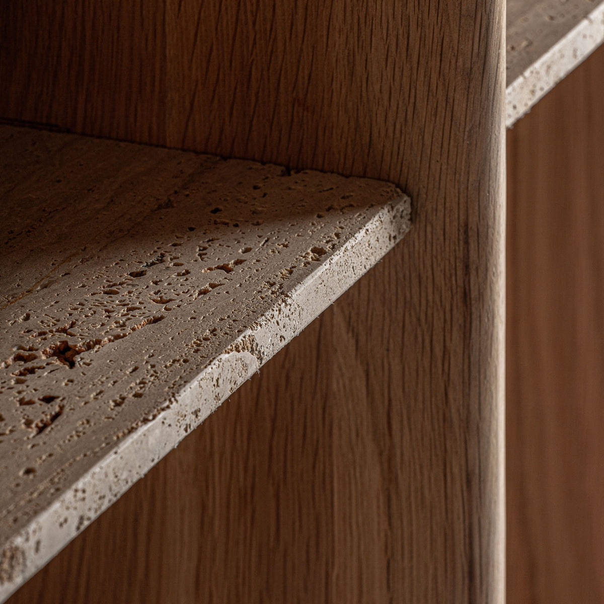 Primer plano del acabado en travertino poroso de la estantería modular Nara – estilo natural y sofisticado