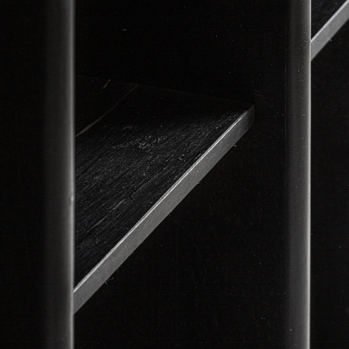 Primer plano de unión entre estantes y módulo en madera negra mate – diseño sobrio de autor