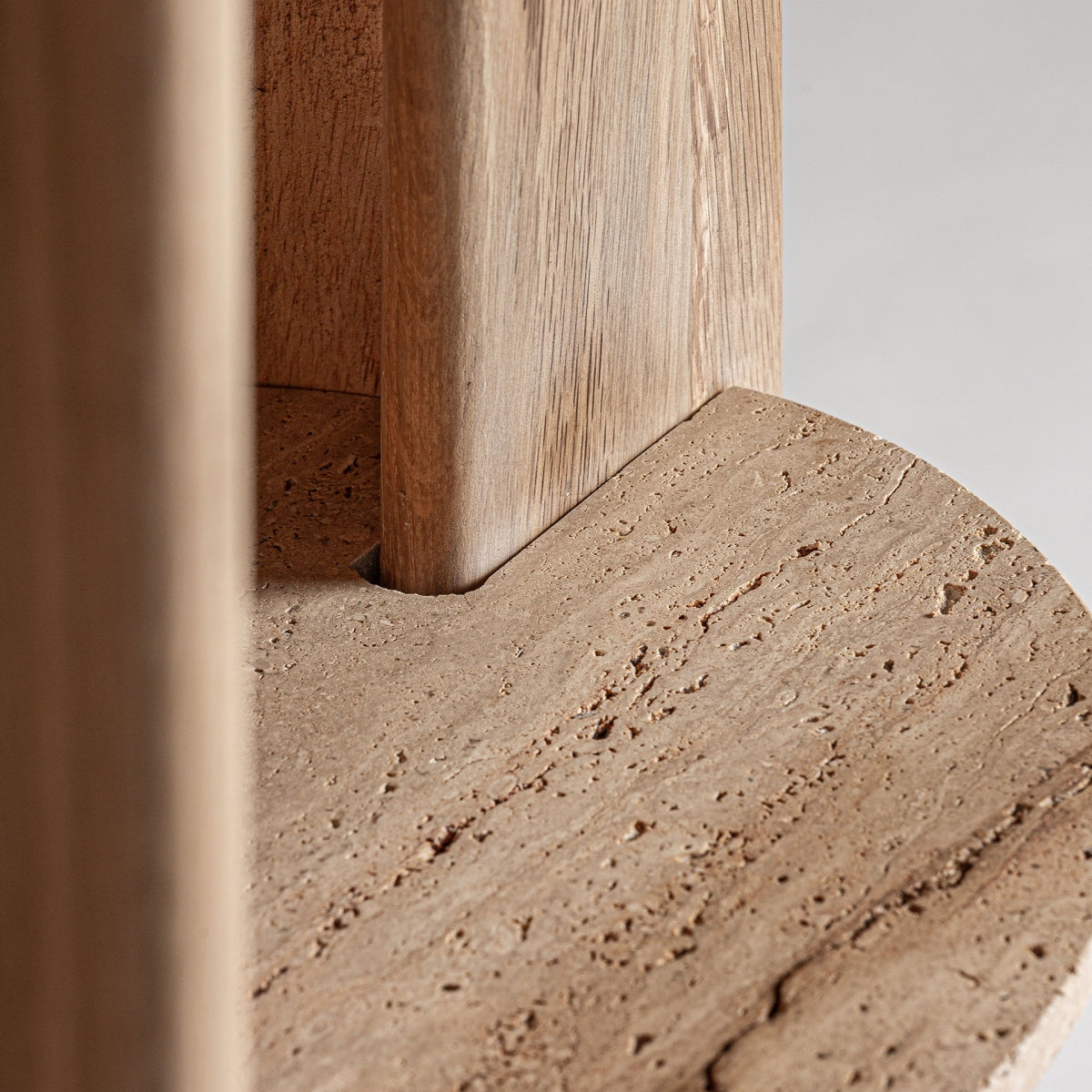Detalle de la base curva en travertino natural de la estantería, diseño elegante y minimalista