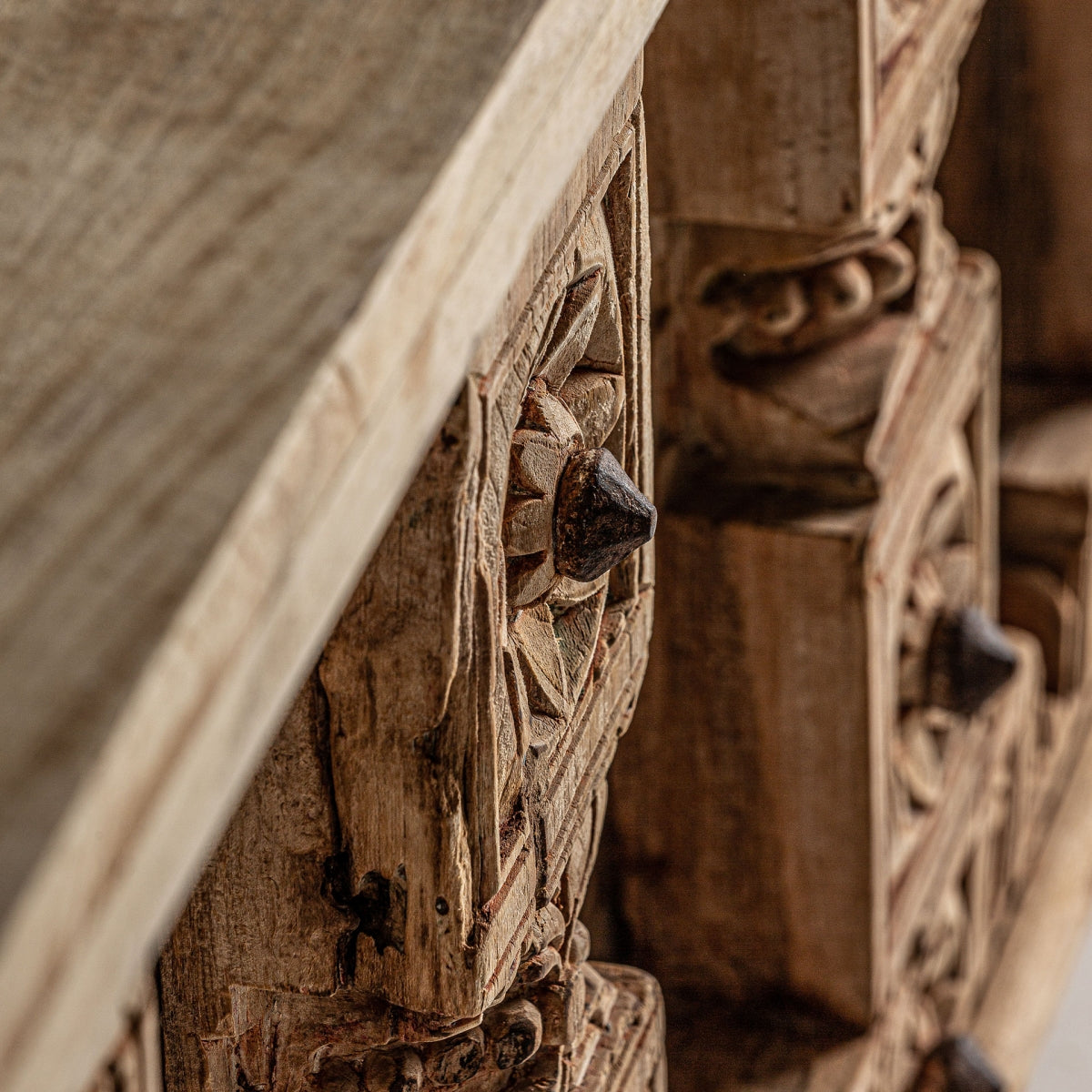 Detalle de talla floral en relieve del baúl PHALODI, textura natural de madera, trabajo artesanal auténtico.
