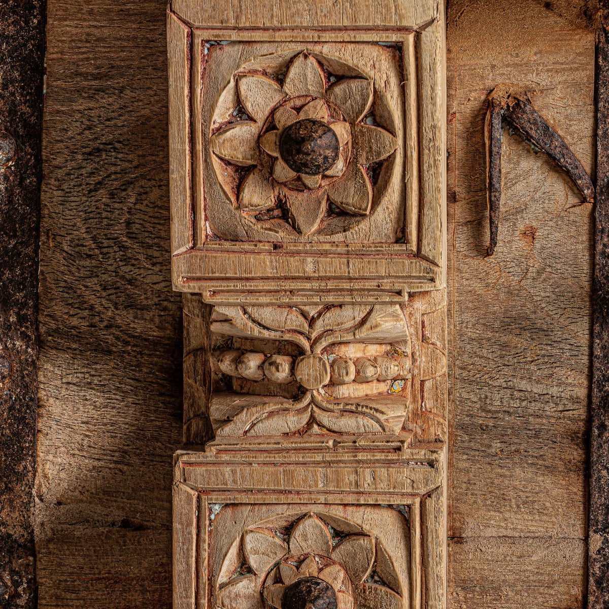 Detalle decorativo del frontal tallado del baúl PHALODI con flor de ocho pétalos, acabado envejecido y textura cálida.