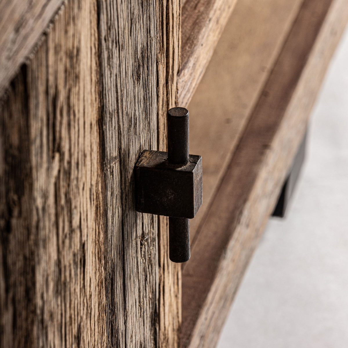 Primer plano del tirador de hierro negro sobre madera oscura, contraste industrial y auténtico.