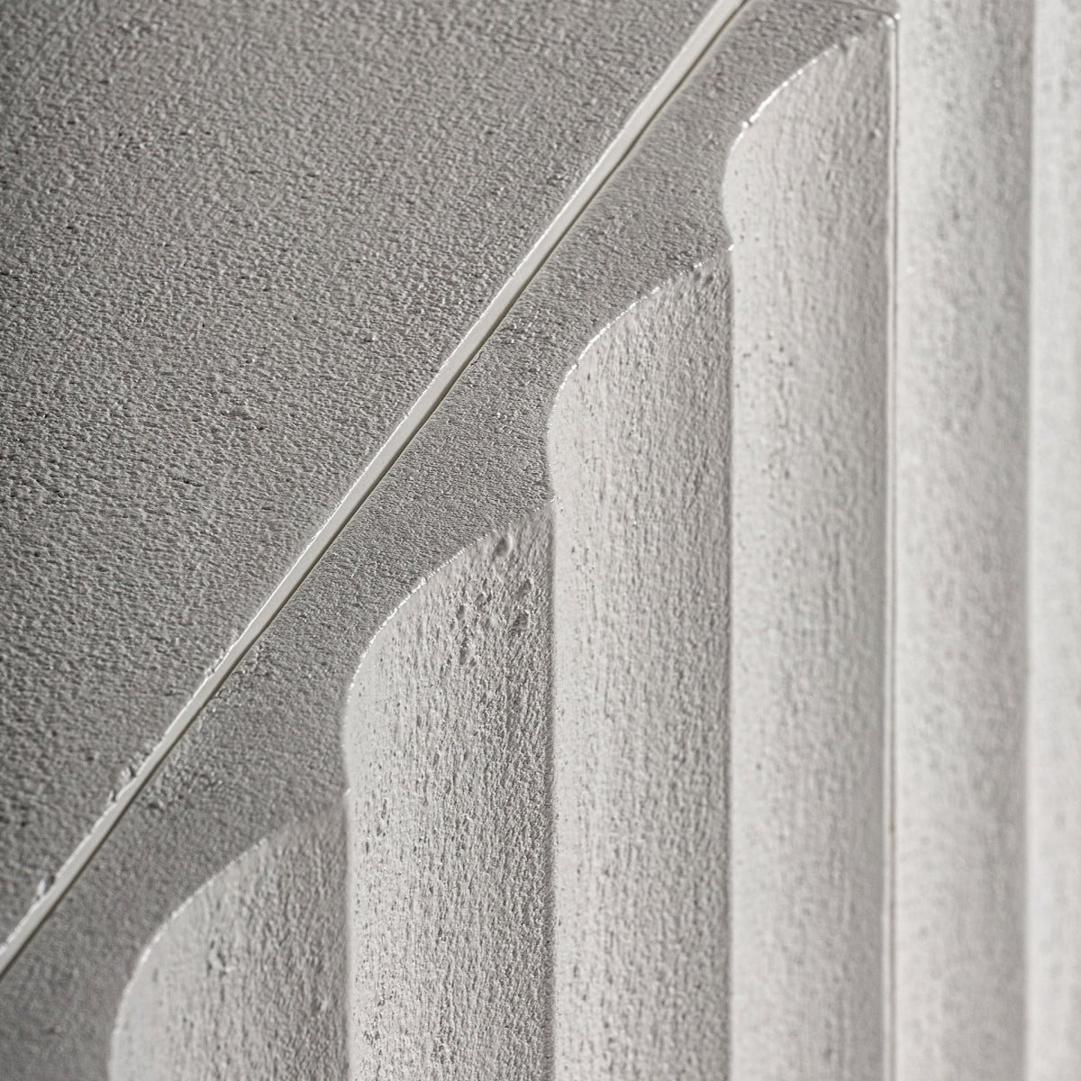 Detalle de textura y acabado rugoso del aparador blanco, con líneas talladas y geometría escultórica.