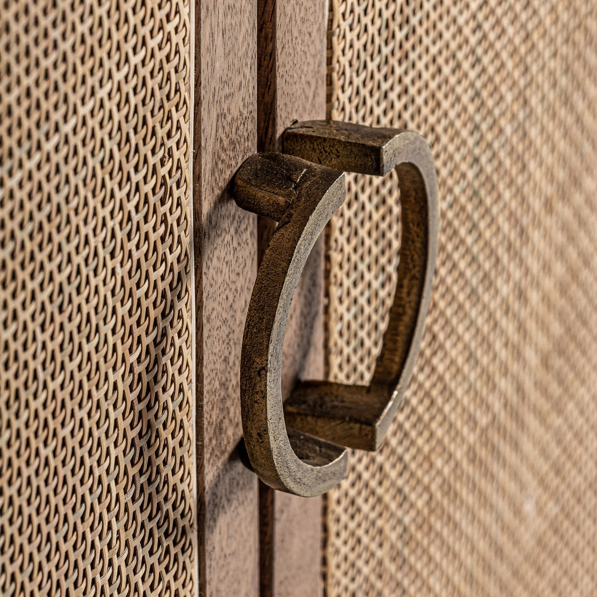 Primer plano del tirador metálico en forma de anilla, acento vintage sobre madera natural.