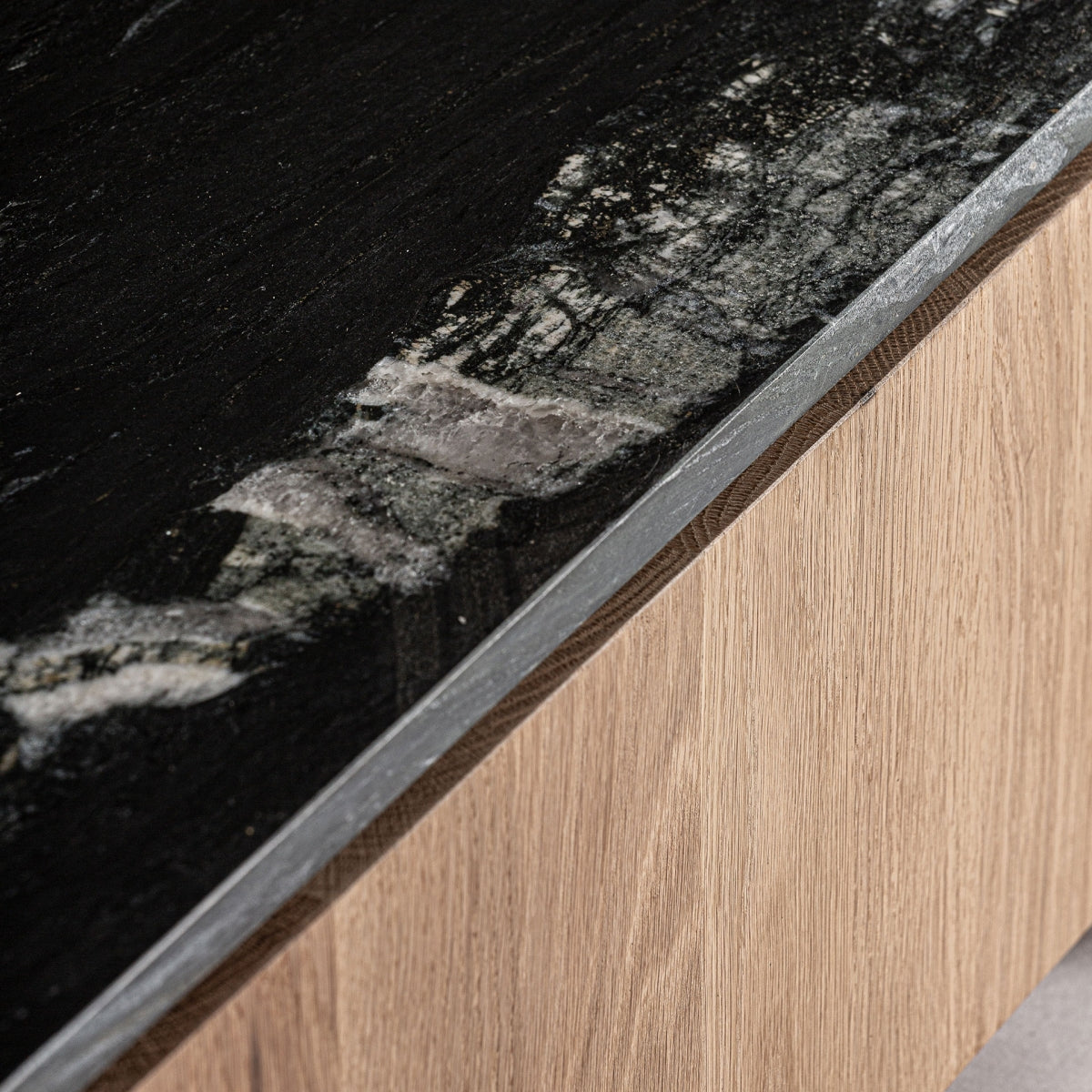 Primer plano del sobre de piedra negra del mueble de TV Nara, con vetas naturales que aportan sofisticación.
