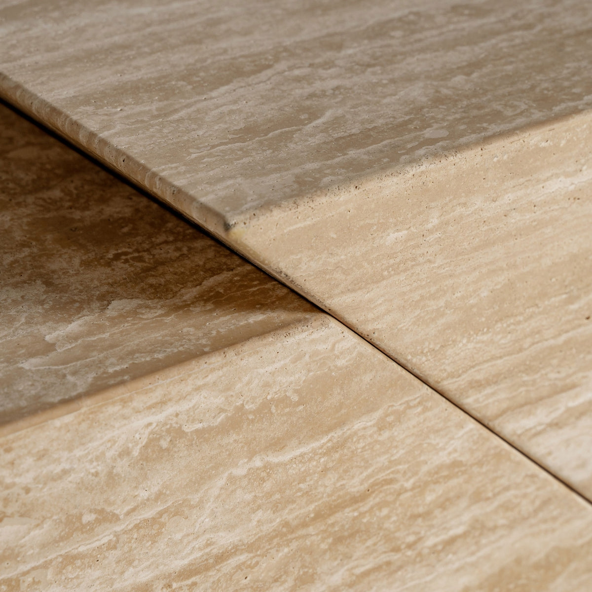 Detalle del sobre superior del mueble Thiennes, mostrando la textura porosa y elegante del travertino.